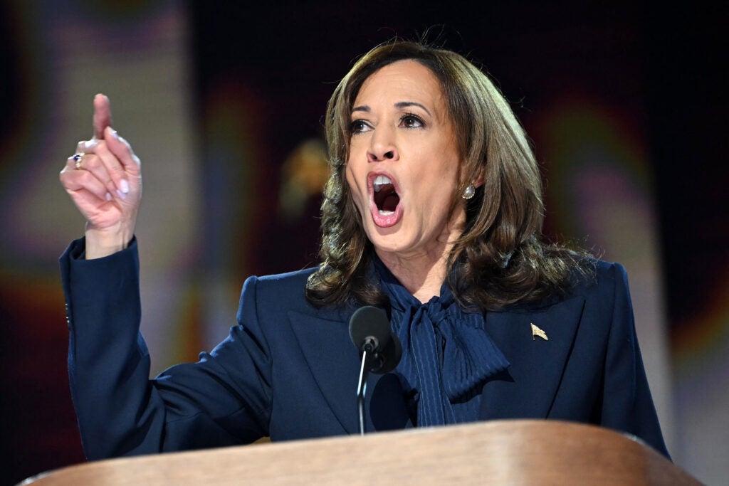 Kamala Harris with finger raised in a blue suit.