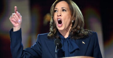 Kamala Harris with finger raised in a blue suit.