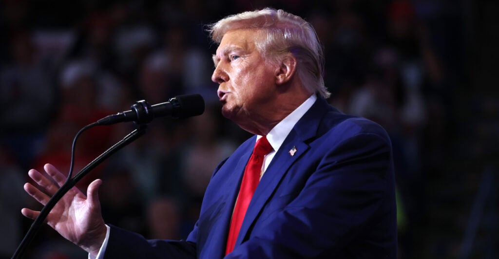 Donald Trump in a blue suit speaks at a rally.