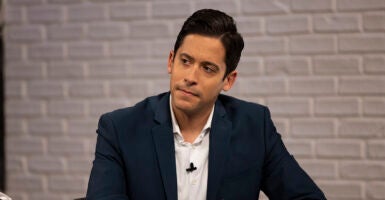 Michael Knowles in a black sport coat and a white shirt stares intently