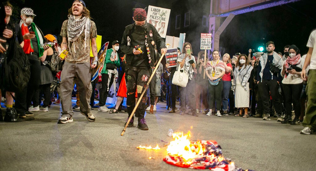 Anti-Israel protesters burn an American flag outside the DNC.