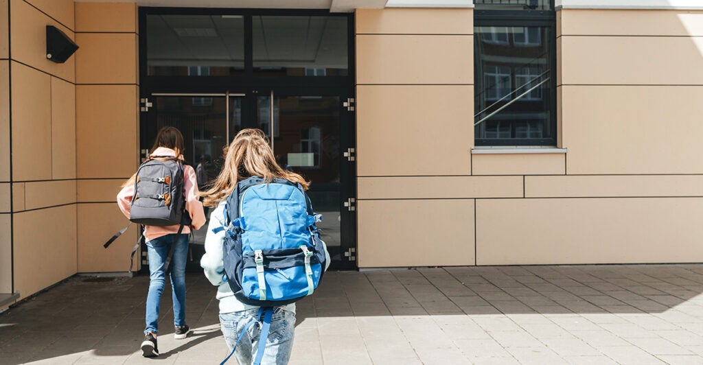 Kids run into school with backpacks