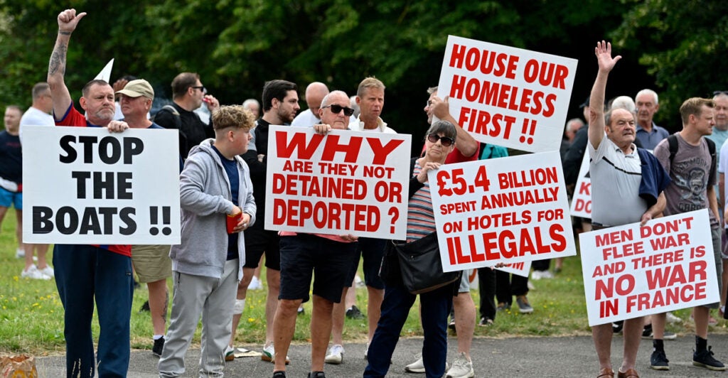 Protesters hold up signs against illegal immigration in Britain.