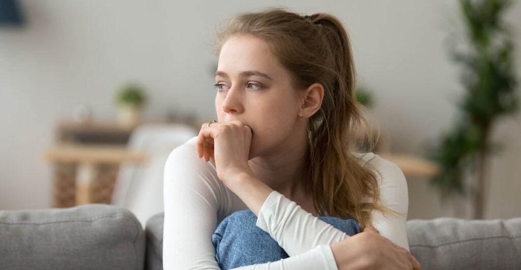 A young woman on a couch looking worried