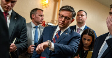 Mike Johnson in blue suit checking watch