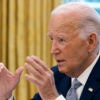 Joe Biden in a blue suit gestures in the White House