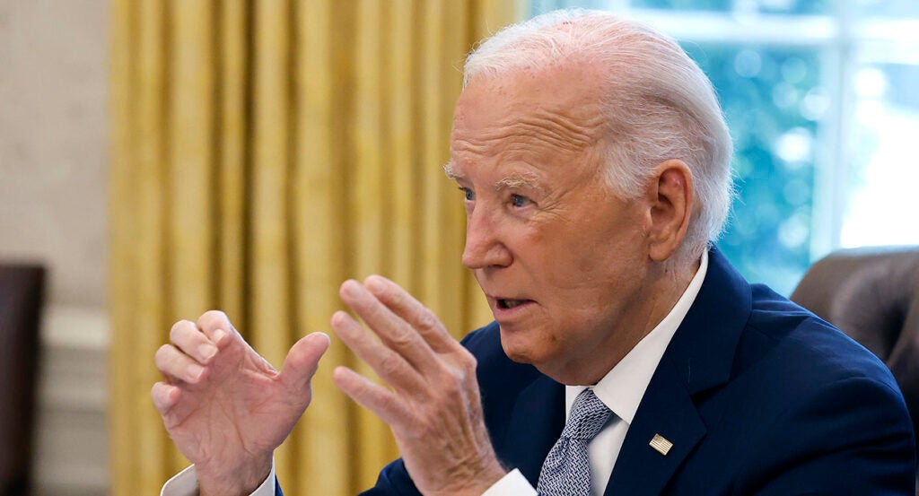 Joe Biden in a blue suit gestures in the White House