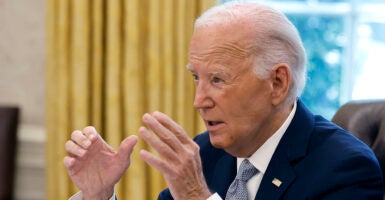 Joe Biden in a blue suit gestures in the White House