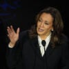 Kamala Harris in a suit leans left, gesturing