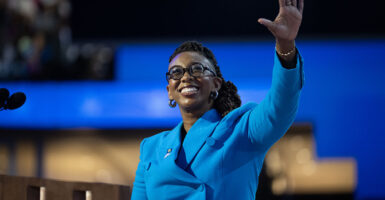 Kelley Robinson in a blue suit raises her hand