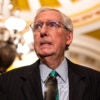 Mitch McConnell bites his lip in a suit