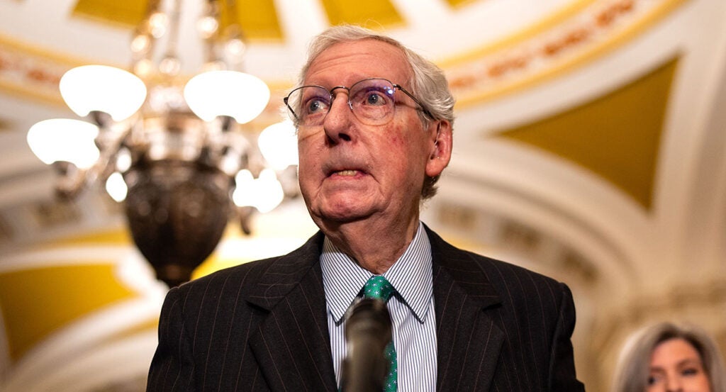 Mitch McConnell bites his lip in a suit