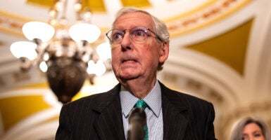 Mitch McConnell bites his lip in a suit