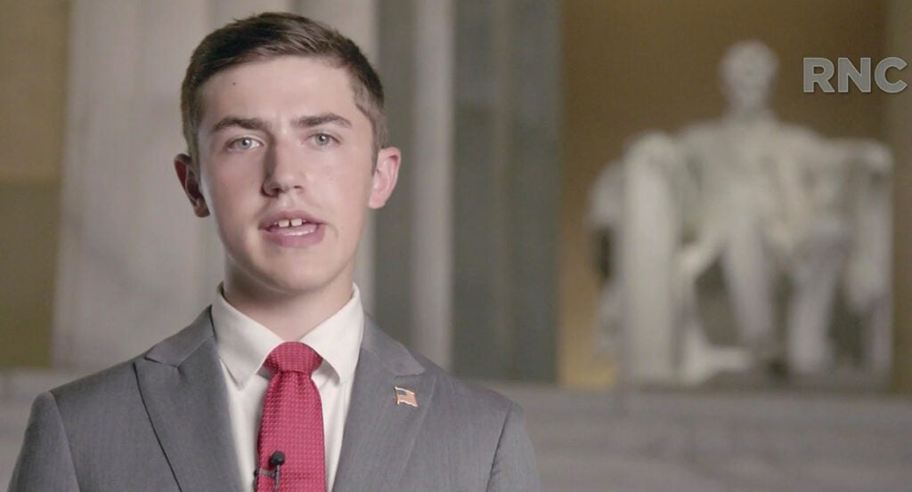 Nick Sandmann in a suit in front of Abraham Lincoln