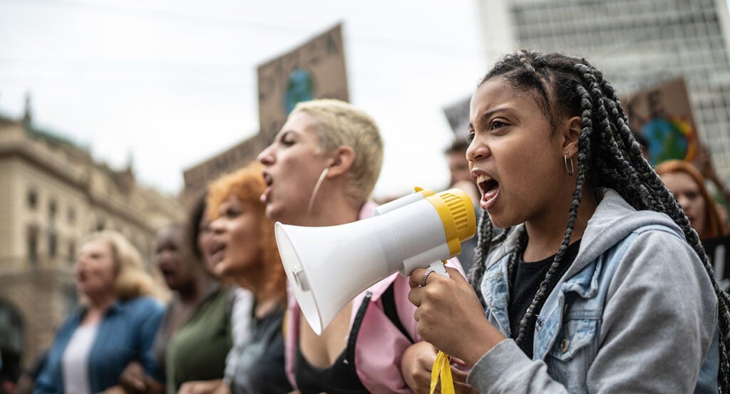 Women shout in protest as a girl holds a bullhorn