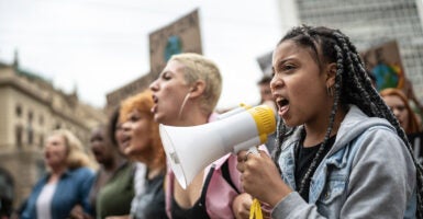 Women shout in protest as a girl holds a bullhorn