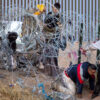 Five illegal immigrant men trying to climb under razor wire at the US-Mexico border