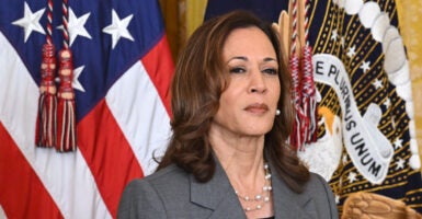 kamala Harris in a suit with an American flag Behind her