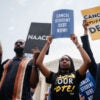 Young people stand in front of the Supreme Court holding up signs Calling for the cancellation of student loan debt