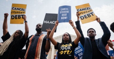 Young people stand in front of the Supreme Court holding up signs Calling for the cancellation of student loan debt