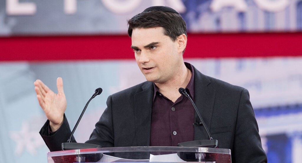 Ben Shapiro gestures in a suit at CPAC