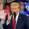 Donald Trump speaks at a campaign rally in a blue suit and red tie