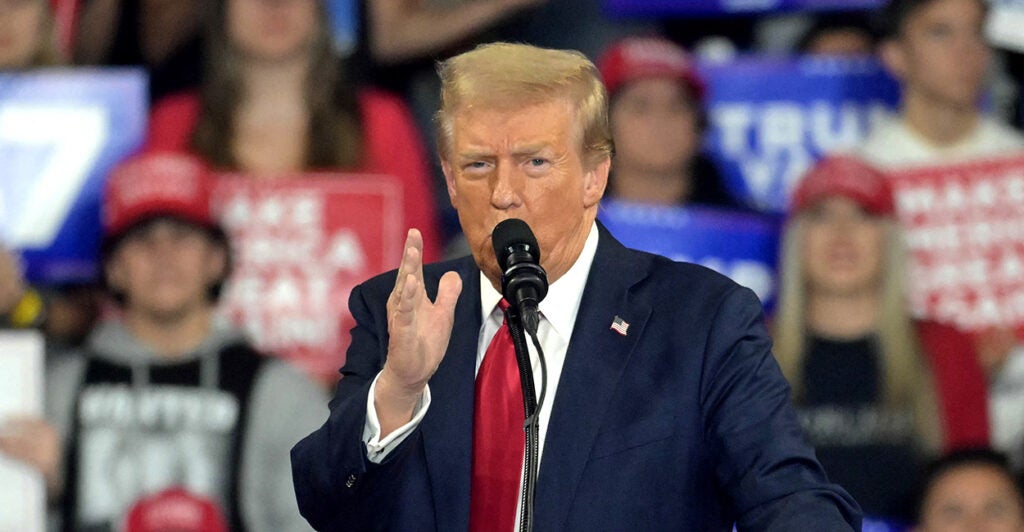 Donald Trump speaks at a campaign rally in a blue suit and red tie