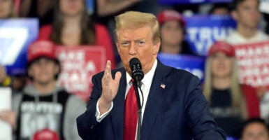 Donald Trump speaks at a campaign rally in a blue suit and red tie