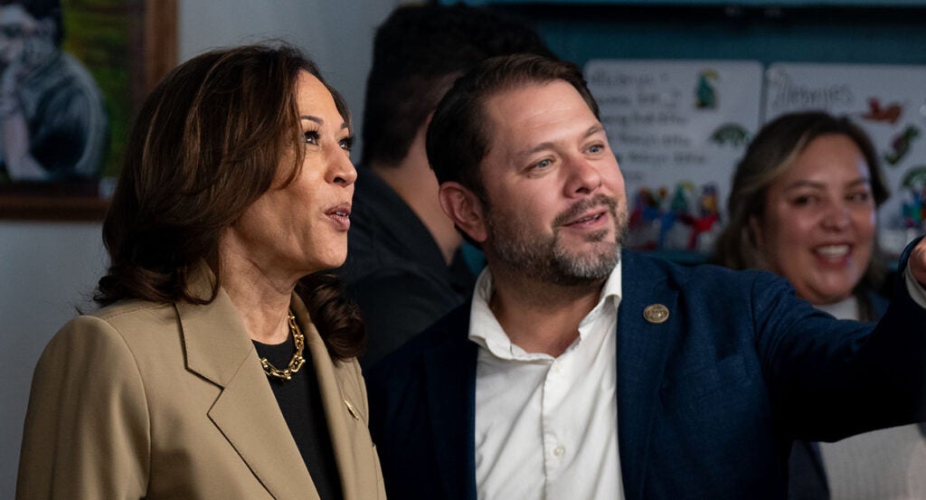 Kamala Harris in a tan sport coat stands by Ruben Gallego in a blue suit