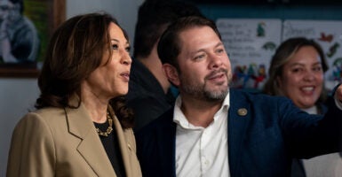 Kamala Harris in a tan sport coat stands by Ruben Gallego in a blue suit