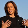 Kamala Harris gestures while wearing a black suit