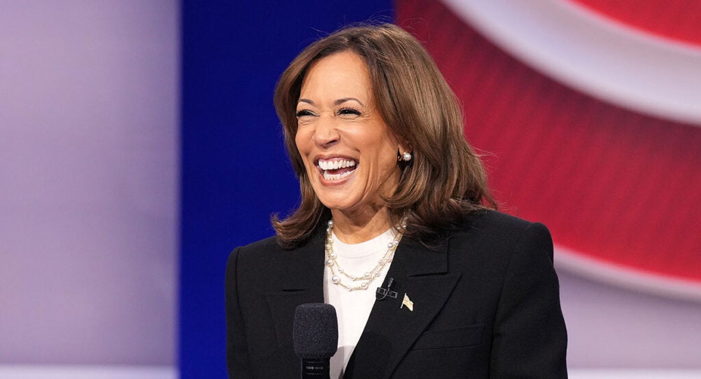 Kamala Harris in a white shirt and a black sport coat laughs