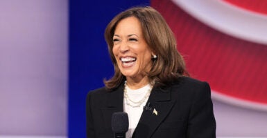 Kamala Harris in a white shirt and a black sport coat laughs