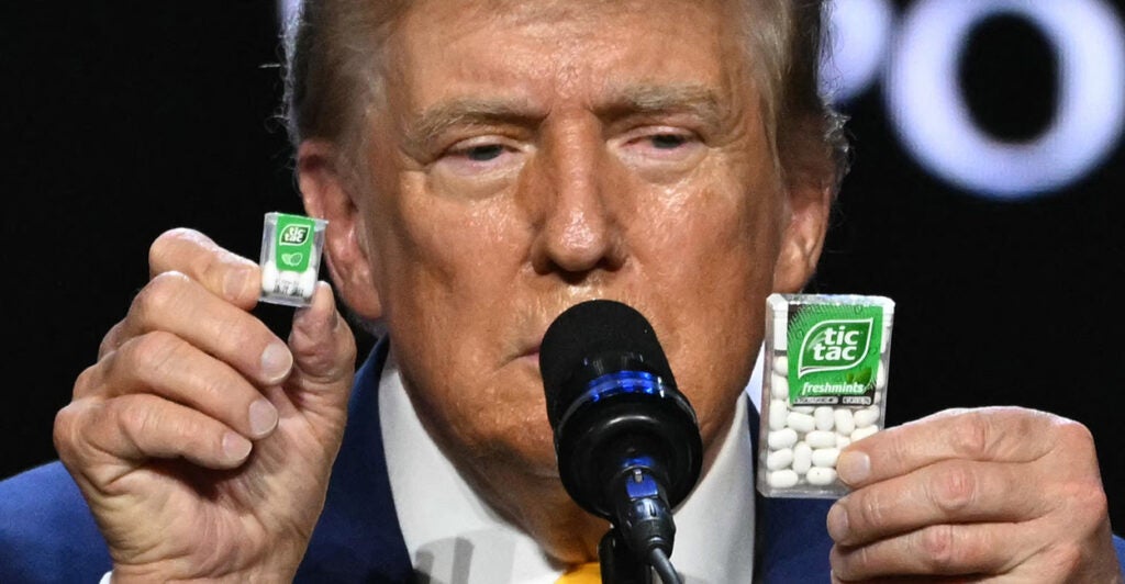 Donald Trump At a microphone holds a big and a small box of Tic-Tac mints to illustrate inflation