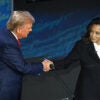 Donald Trump in a blue suit shakes hands with Kamala Harris in a black and white suit