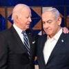 Joe Biden and Benjamin Netanyahu on stage In an embrace with American and Israeli flags behind them