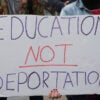 A student at a protest holding a handwritten sign saying, "education, not deportation."