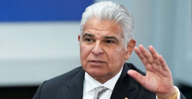 Panama's President Jose Raul Mulino in a suit with his hand raised