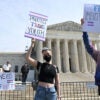 Transgender activists holding up signs for transgender "rights" gather in front of the U.S. Supreme Court