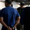 In a parking garage, the Guatemalan National Civil Police take handcuffed human traffickers to a court appearance