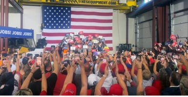 Sen. JD Vance speaks at a factory with a large American flag as his backdrop.