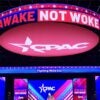 A sign that says "AWAKE NOT WOKE" hangs over the stage before the Conservative Political Action Conference meeting.