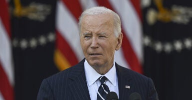 US President Joe Biden, in a suit, stands before the United States flag and addresses the nation following Trump's 2024 presidential election victory.