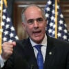 Bob Casey in a black suit raises his fist