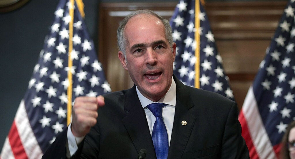 Bob Casey in a black suit raises his fist