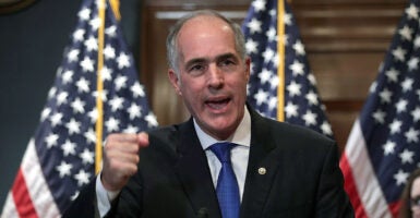 Bob Casey in a black suit raises his fist