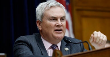 Representative James Comer in a gray suit and red tie and a microphone in a House committee meeting