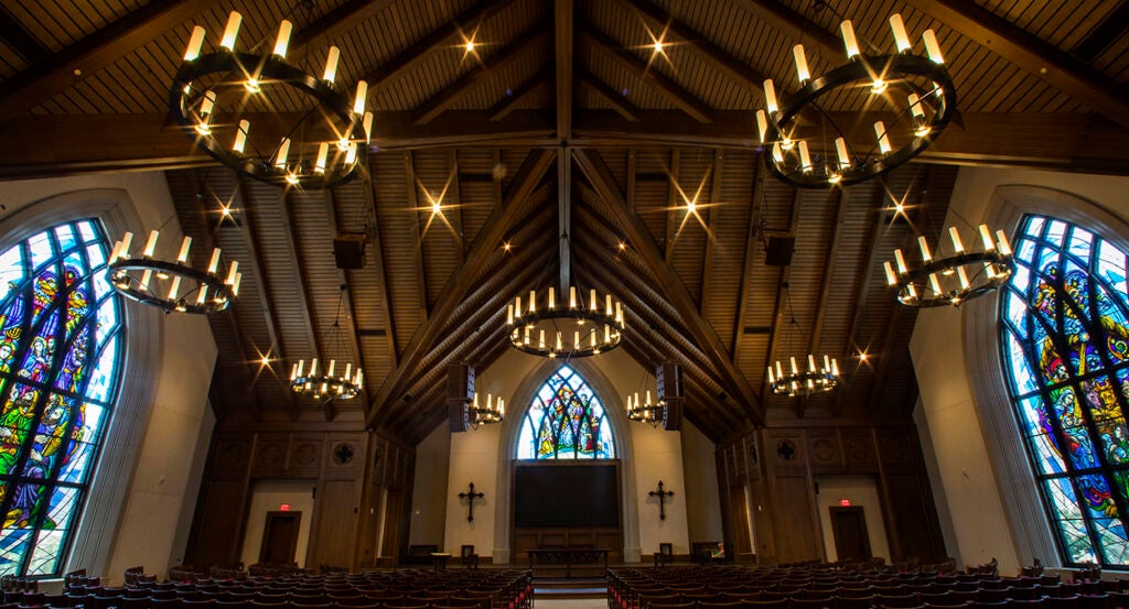 The interior of Parish Life Center in Houston, Texas, with stained glass windows and candles