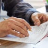 Close-up of a man holding a tax form, working from home. (Thanasis/Getty Images)