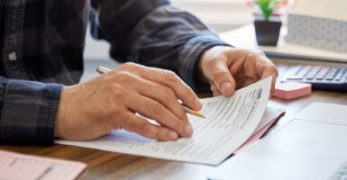 Close-up of a man holding a tax form, working from home. (Thanasis/Getty Images)